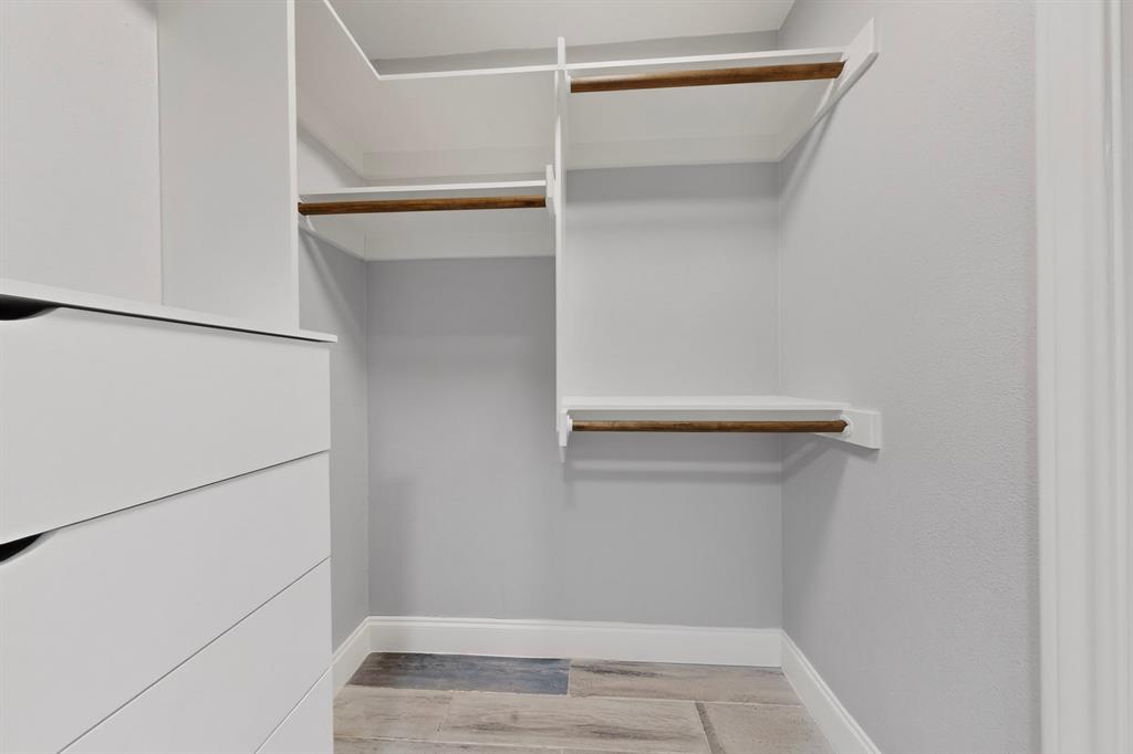 7631 Meadow Road Dallas, TX 75230 - Photo 29 of 40 A bright, spacious walk-in closet featuring white drawers and shelves, organized for easy access to clothing and accessories.