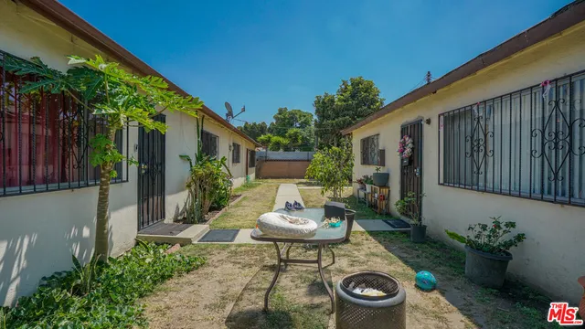 a backyard of a house with table and chairs plants with wooden fence