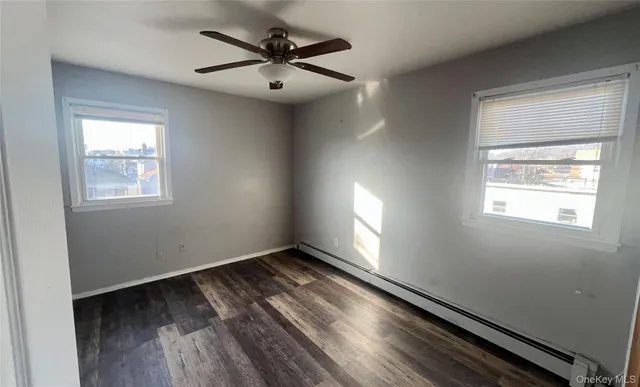 an empty room with wooden floor fan and windows