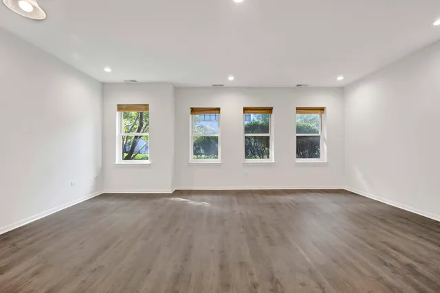 a view of an empty room with wooden floor and window