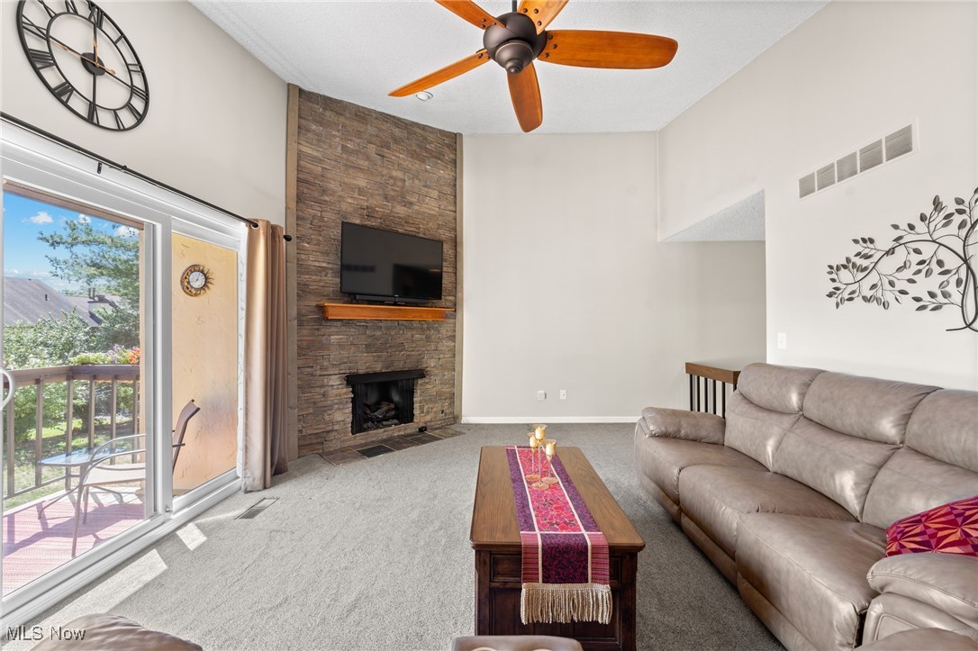 889 Hampton Ridge Drive Akron, OH 44313 - Photo 13 of 38 Living room featuring carpet floors, a high ceiling, ceiling fan, and a stone fireplace