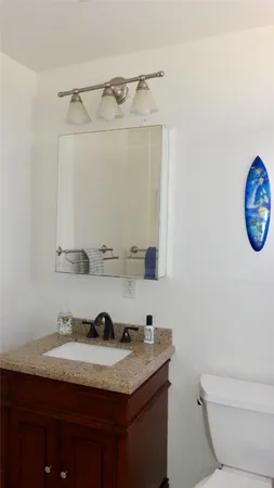 a bathroom with a granite countertop sink a toilet and a mirror