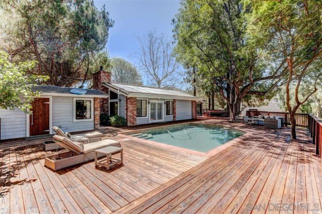 a view of a house with sitting area and large trees
