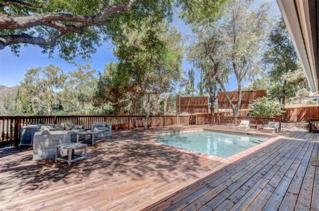 a view of a swimming pool with a patio and wooden fence