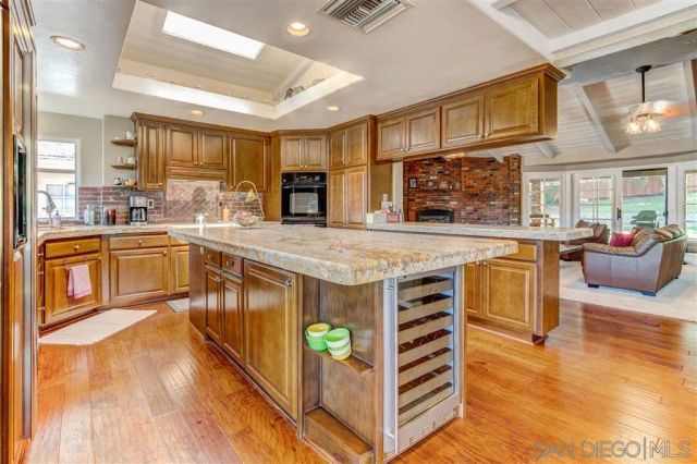 a view of a kitchen counter top space with stainless steel appliances wooden floor and living room view