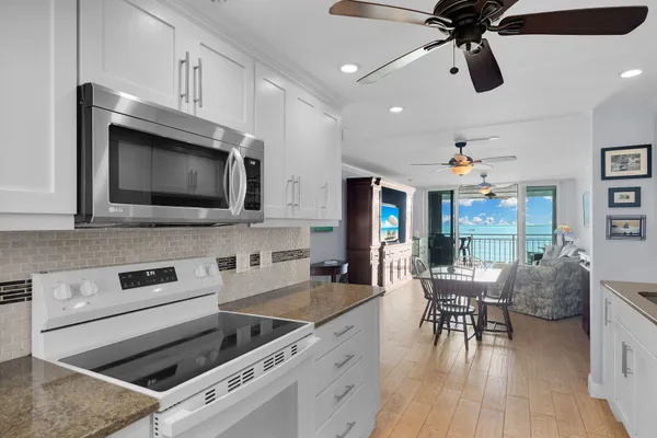a large kitchen with stainless steel appliances a refrigerator a sink dishwasher and white cabinets with wooden floor