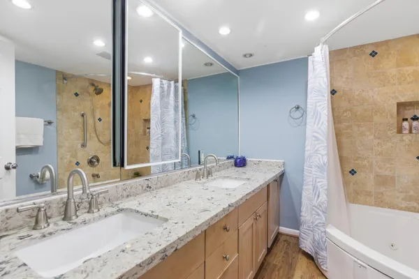 a bathroom with a granite countertop sink mirror and a bath tub