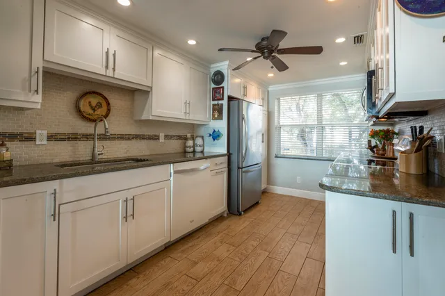 a kitchen with stainless steel appliances granite countertop a sink a stove and a refrigerator