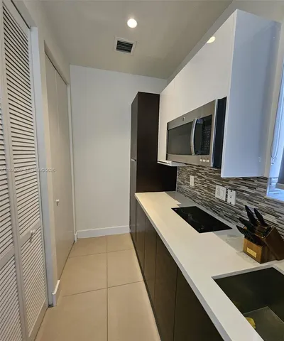 a kitchen with a sink and a stove top oven with wooden floor
