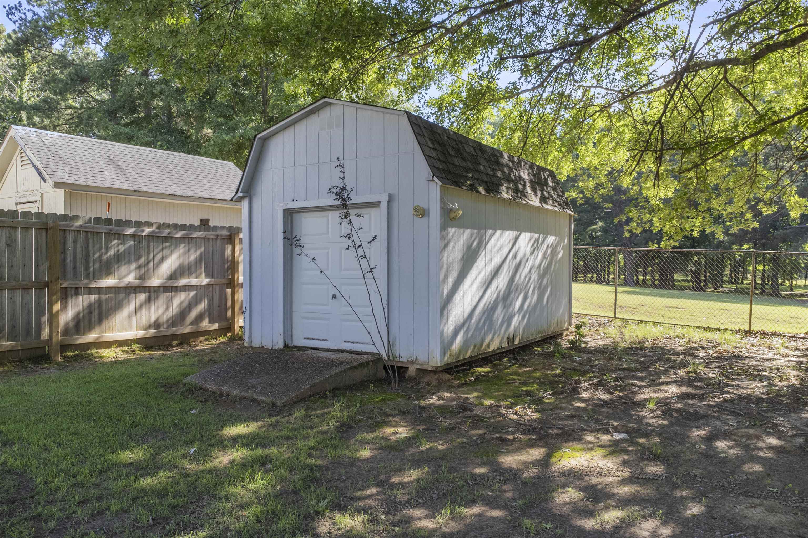 4279 High Plains Road Bartlett, TN 38135 - Photo 7 of 37 White utility shed with a gambrel roof and a rollup garage door, featuring a concrete ramp entry