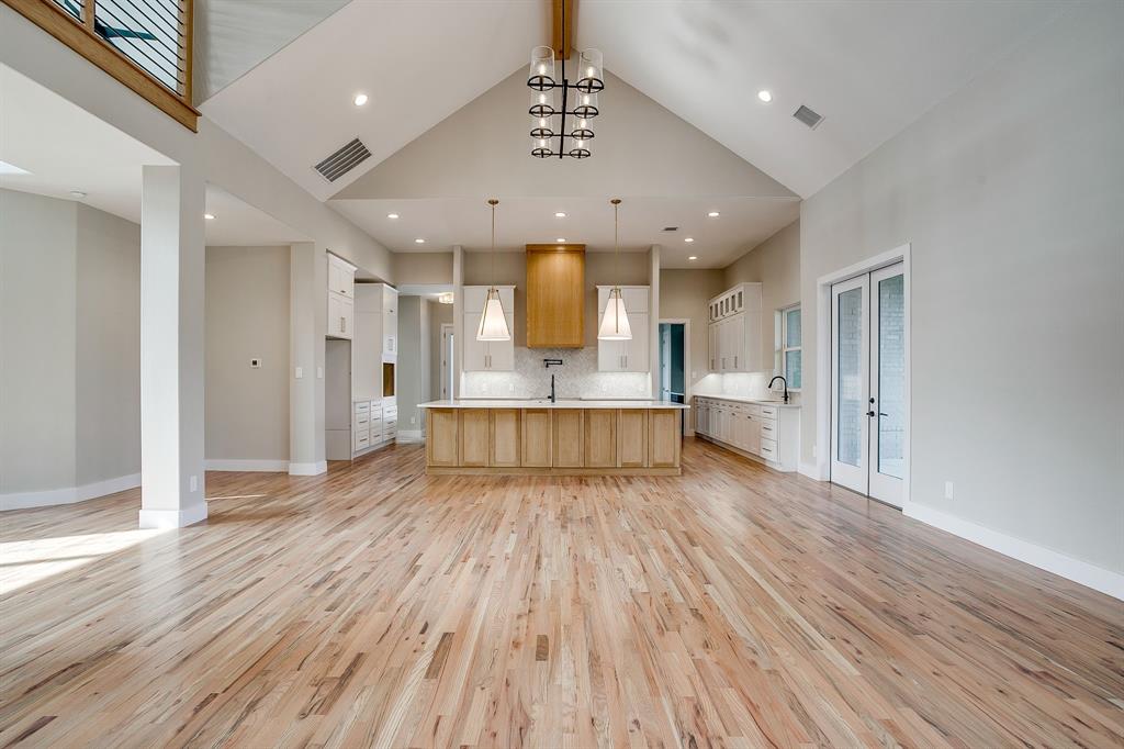 456 Acorn Trail Granbury, TX 76049 - Photo 17 of 40 a view of a room with wooden floor a ceiling fan and kitchen space
