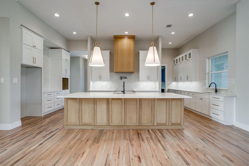 456 Acorn Trail Granbury, TX 76049 - Photo 3 of 40 a large kitchen with sink wooden floor white cabinets and stainless steel appliances