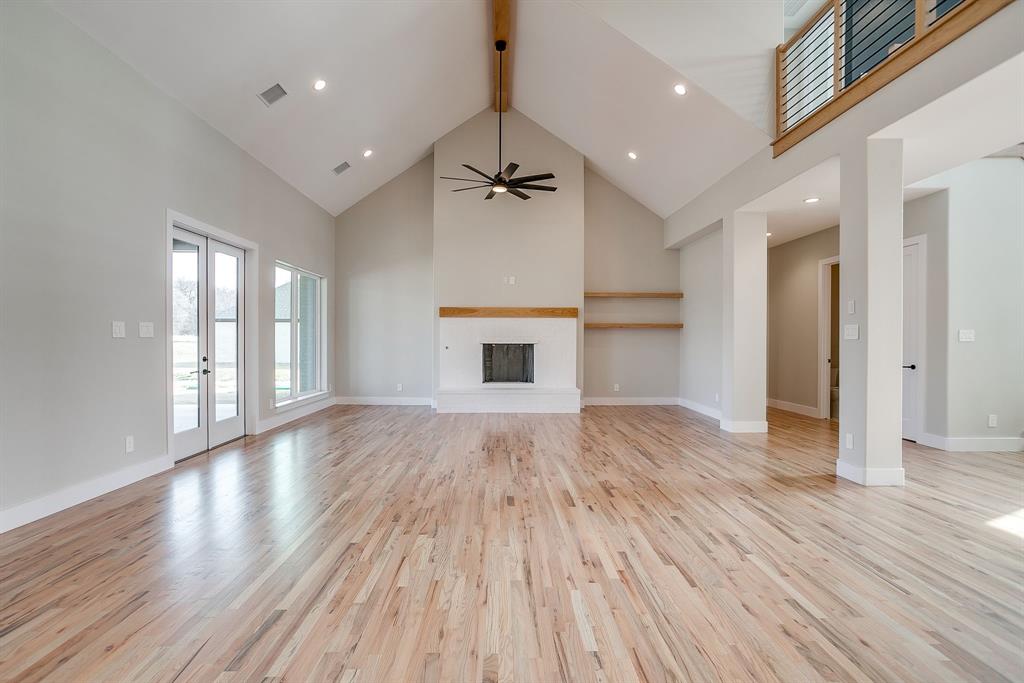 456 Acorn Trail Granbury, TX 76049 - Photo 5 of 40 an empty room with wooden floor ceiling fan and windows