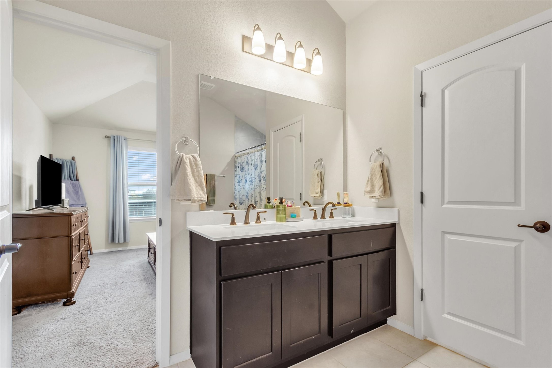 460 Delta Crest Maxwell, TX 78656 - Photo 11 of 18 Bathroom featuring double vanity, a shower with shower curtain, lofted ceiling, and light colored carpet