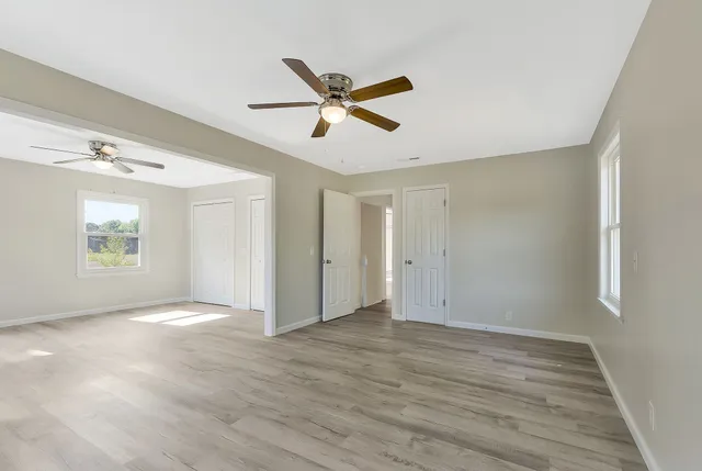 a view of empty room with wooden floor and fan