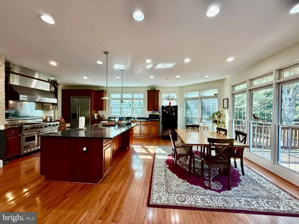 a kitchen with granite countertop a stove a sink a dining table and chairs