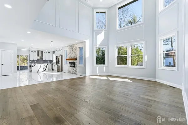 a large white kitchen with stainless steel appliances granite countertop a stove a sink a refrigerator and white cabinets with wooden floor