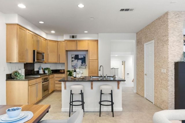 a kitchen with stainless steel appliances kitchen island granite countertop a stove a sink a refrigerator and white cabinets