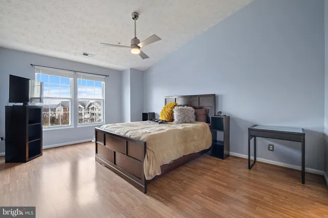 a bedroom with a large bed a chandelier and a flat tv screen on dresser