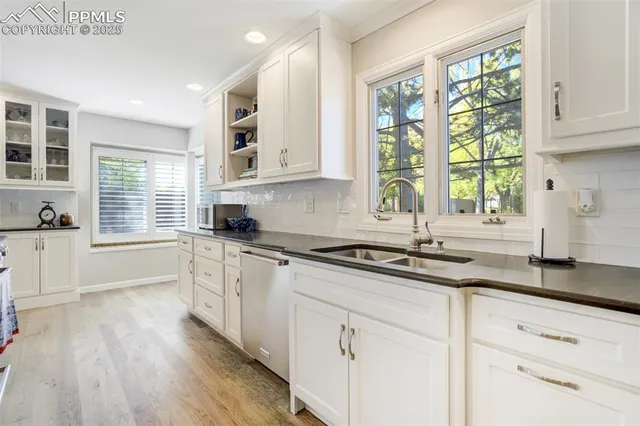 a kitchen with granite countertop white cabinets window and stainless steel appliances