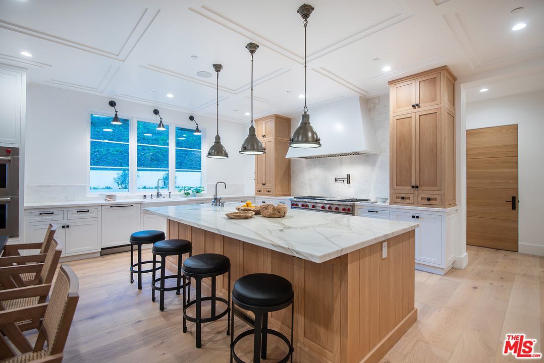5716 Jed Smith Road Hidden Hills, CA 91302 - Photo 11 of 53 a kitchen with a stove a sink a kitchen island with chairs and wooden cabinets