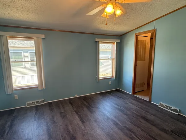 an empty room with wooden floor and windows