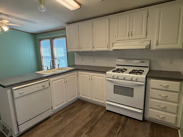 a kitchen with granite countertop white cabinets and white appliances