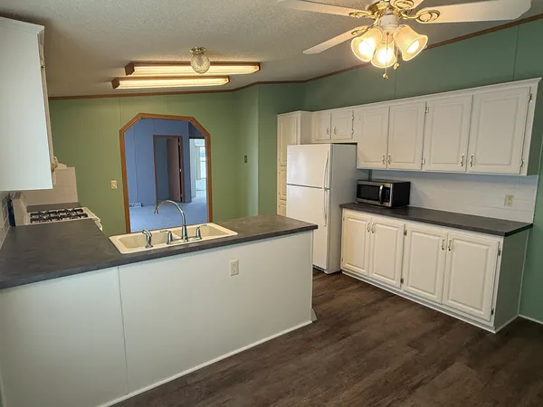 a kitchen with stainless steel appliances a sink cabinets and wooden floor