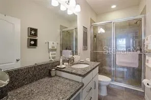 a bathroom with a granite countertop sink toilet and shower