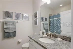 a bathroom with a granite countertop double vanity sink a mirror and a toilet