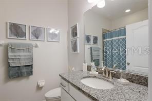8653 Karpeal Drive, Unit 4 Sarasota, FL 34238 - Photo 10 of 14 a bathroom with a granite countertop double vanity sink a mirror and a toilet