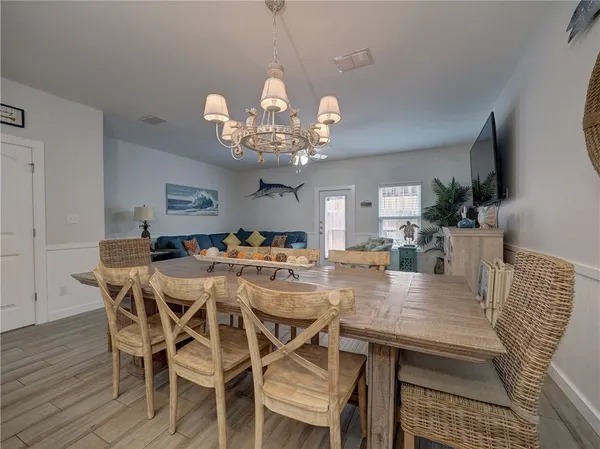 a view of a dining room with furniture a chandelier and wooden floor