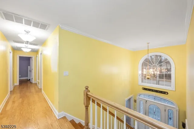 a view of a hallway with wooden floor and chandelier