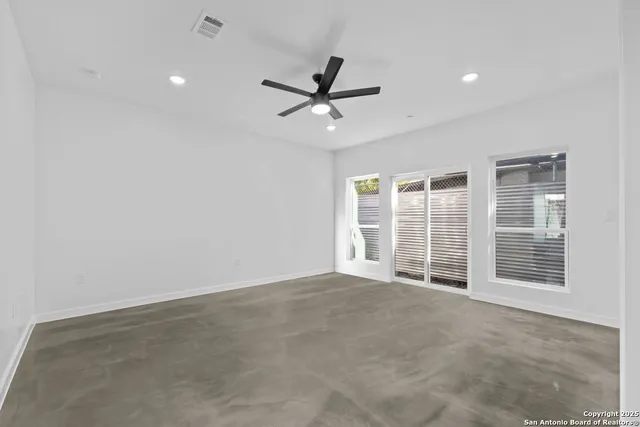 an empty room with windows and ceiling fan