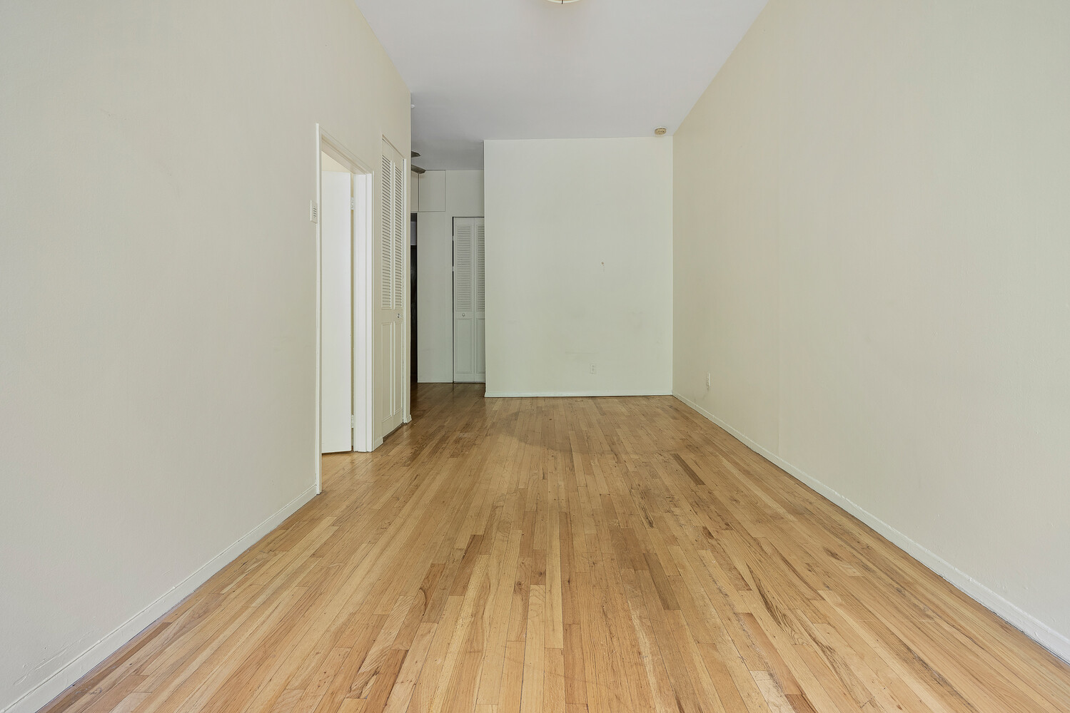 359 West 30th Street, Unit 2B Manhattan, NY 10001 - Photo 11 of 16 a view of a room with wooden floor and white walls