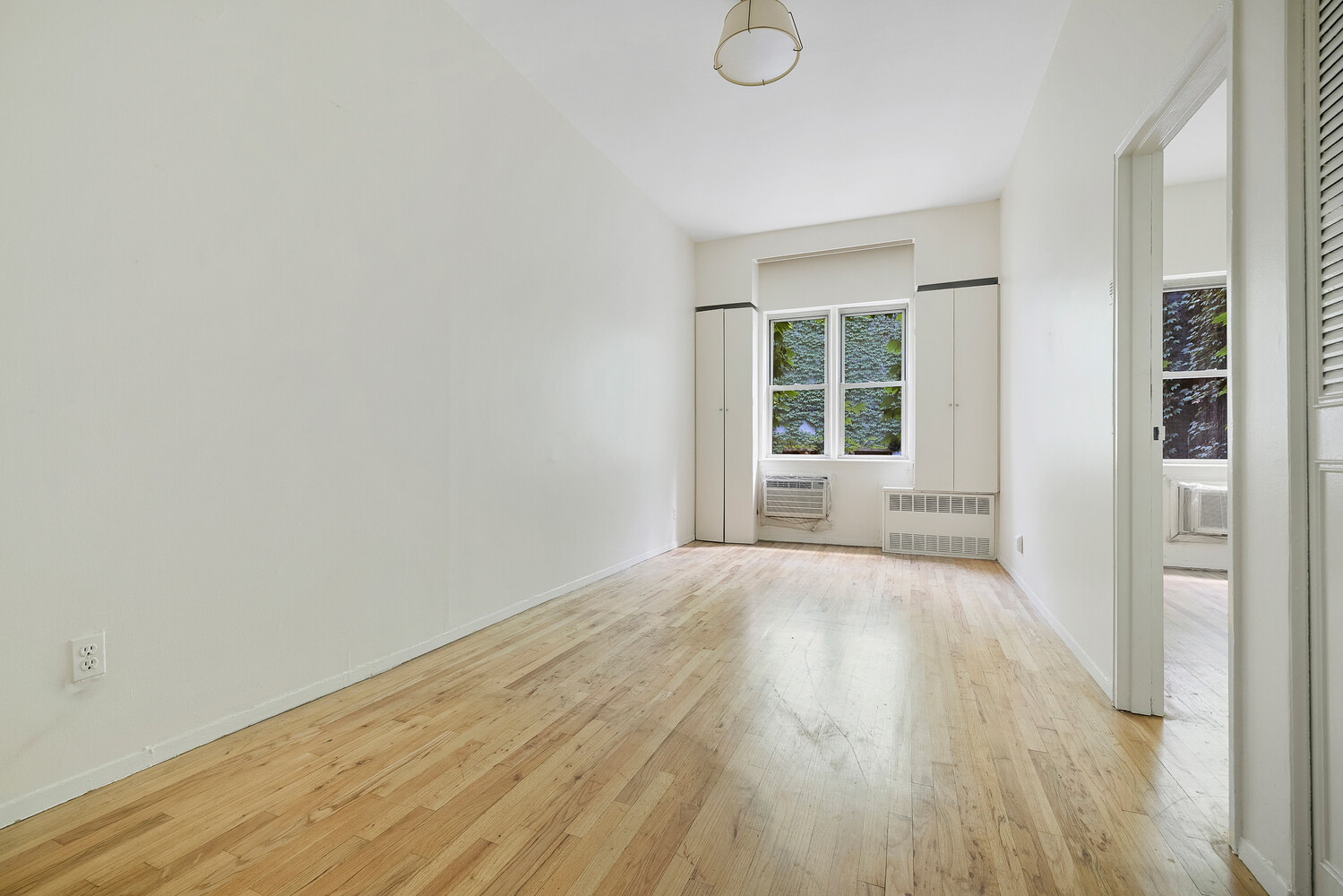 359 West 30th Street, Unit 2B Manhattan, NY 10001 - Photo 9 of 16 a view of an empty room with wooden floor and a window