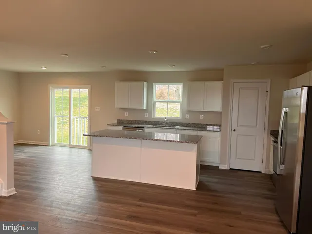 a kitchen with stainless steel appliances granite countertop a refrigerator a sink dishwasher a stove and white countertops with wooden floor