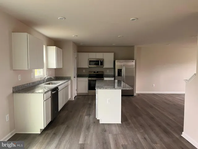 a kitchen with granite countertop a stove top oven a sink dishwasher and a refrigerator with wooden floor