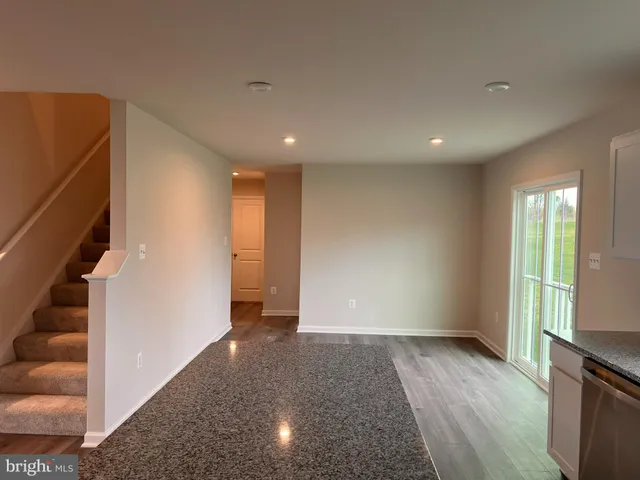 a view of an empty room with wooden floor and windows