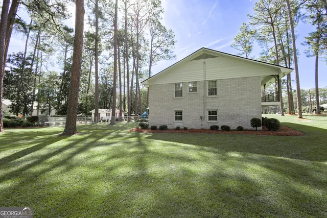 a view of a house with backyard and trees