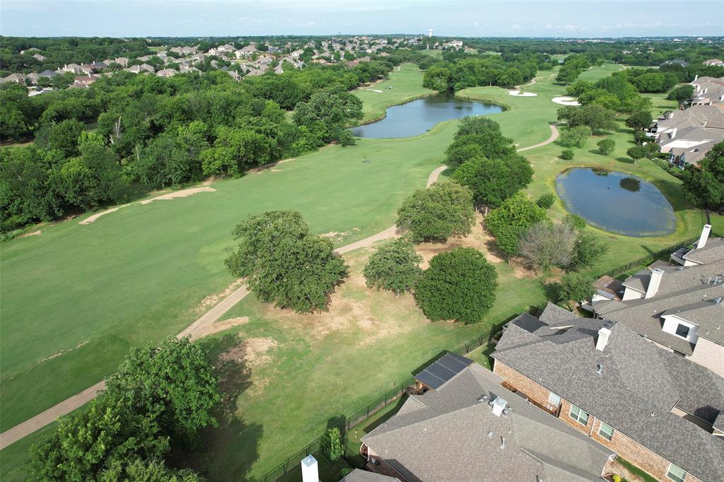 an aerial view of a residential houses with outdoor space and trees all around