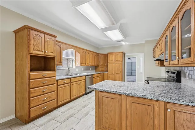 a kitchen with granite countertop a sink stainless steel appliances and cabinets