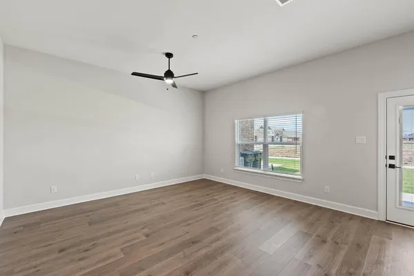 an empty room with wooden floor fan and windows