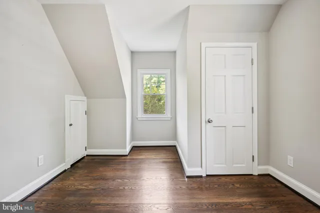 an empty room with wooden floor chandelier fan and windows