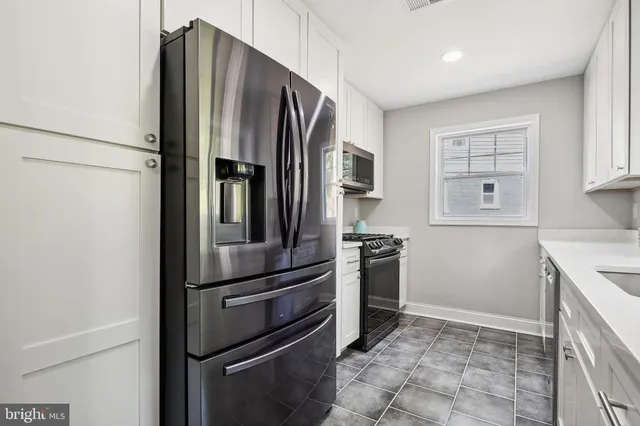 a metallic refrigerator freezer and a stove sitting inside of a kitchen