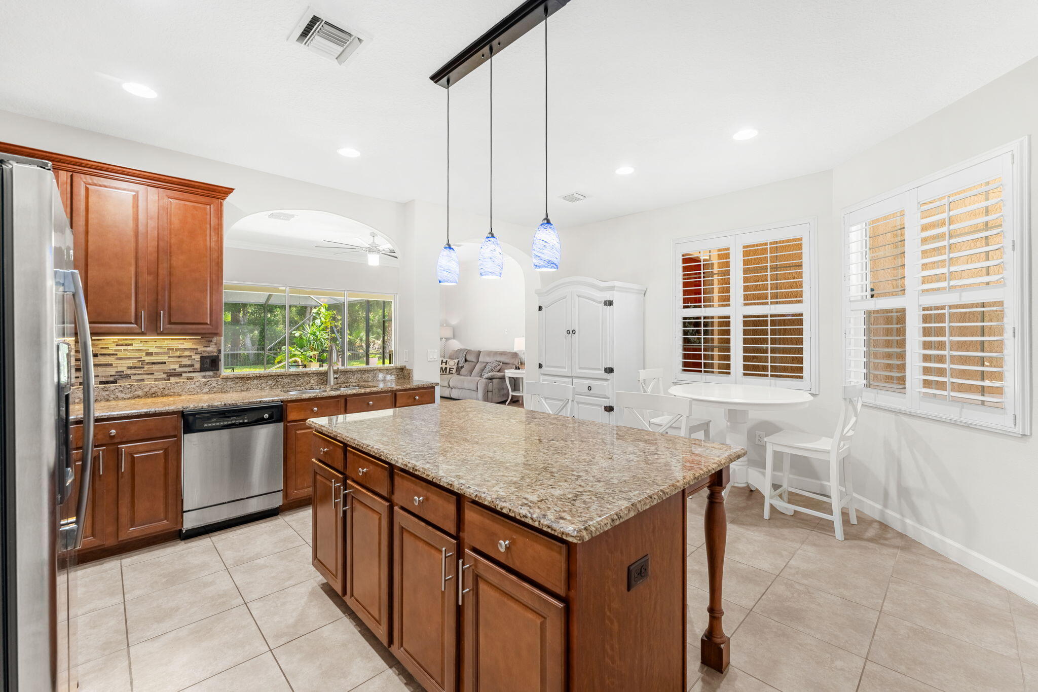 7657 Fieldstone Ranch Square Vero Beach, FL 32967 - Photo 19 of 52 a kitchen with kitchen island granite countertop a table chairs sink and stove