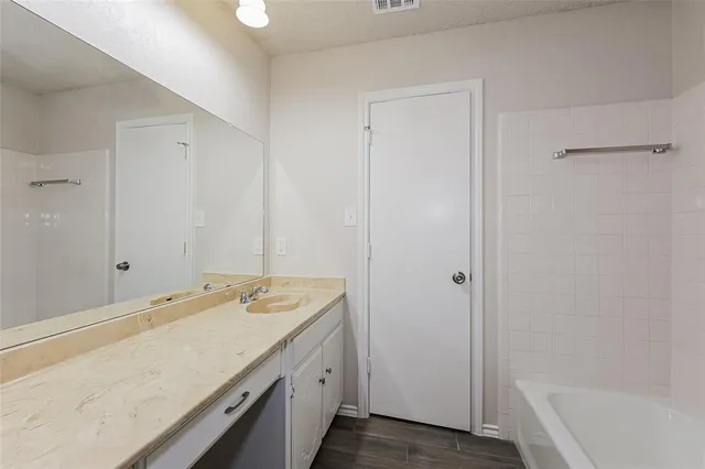 a bathroom with a granite countertop sink and a bathtub