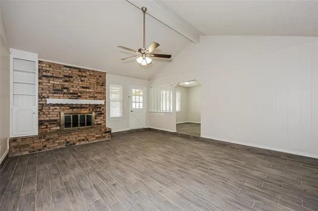 an empty room with windows chandelier fan and fireplace