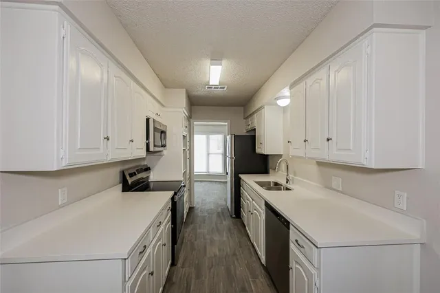 a kitchen that has a lot of cabinets in it and wooden floors