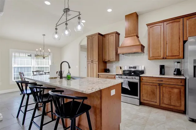 a kitchen with stainless steel appliances granite countertop a kitchen island a stove a table and chairs